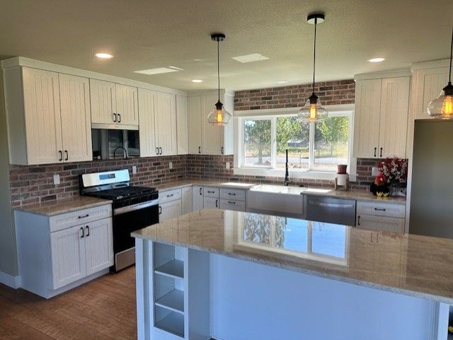 A kitchen with white cabinets , stainless steel appliances , and a large island.