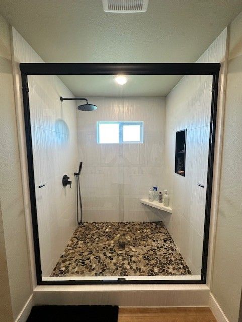 A bathroom with a walk in shower and a window