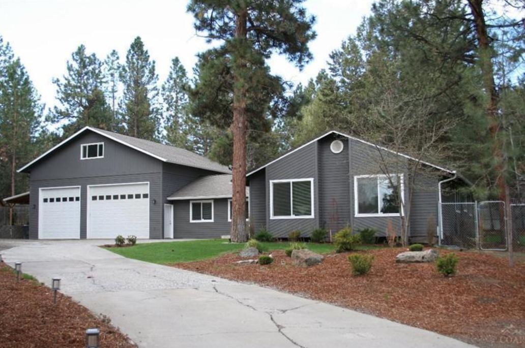 A house with a garage and a driveway surrounded by trees
