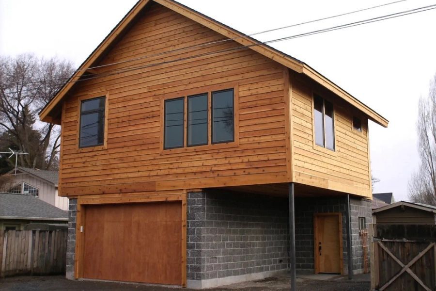 A wooden house with a brick garage underneath it