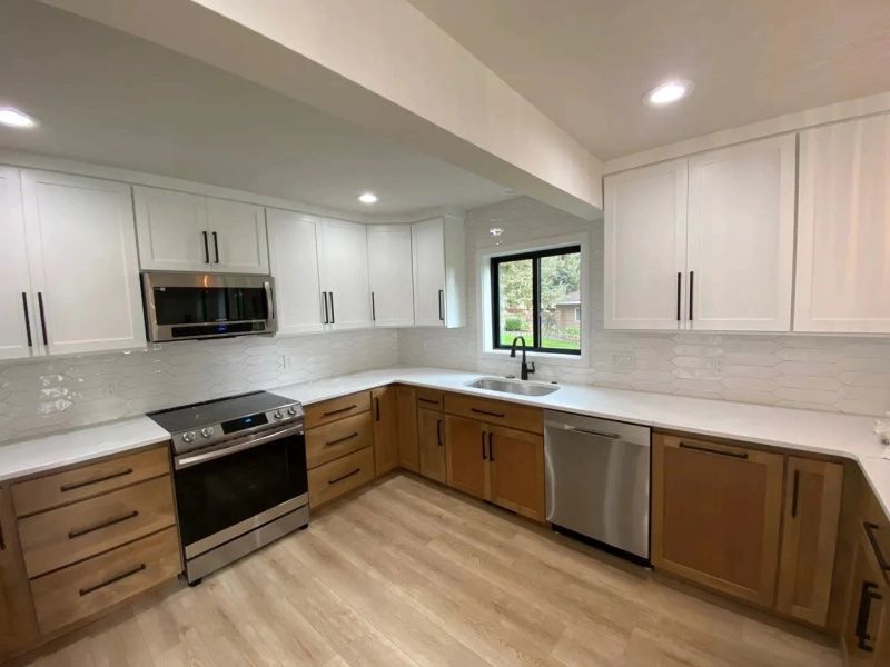 A kitchen with white cabinets , stainless steel appliances , a sink , and a window.