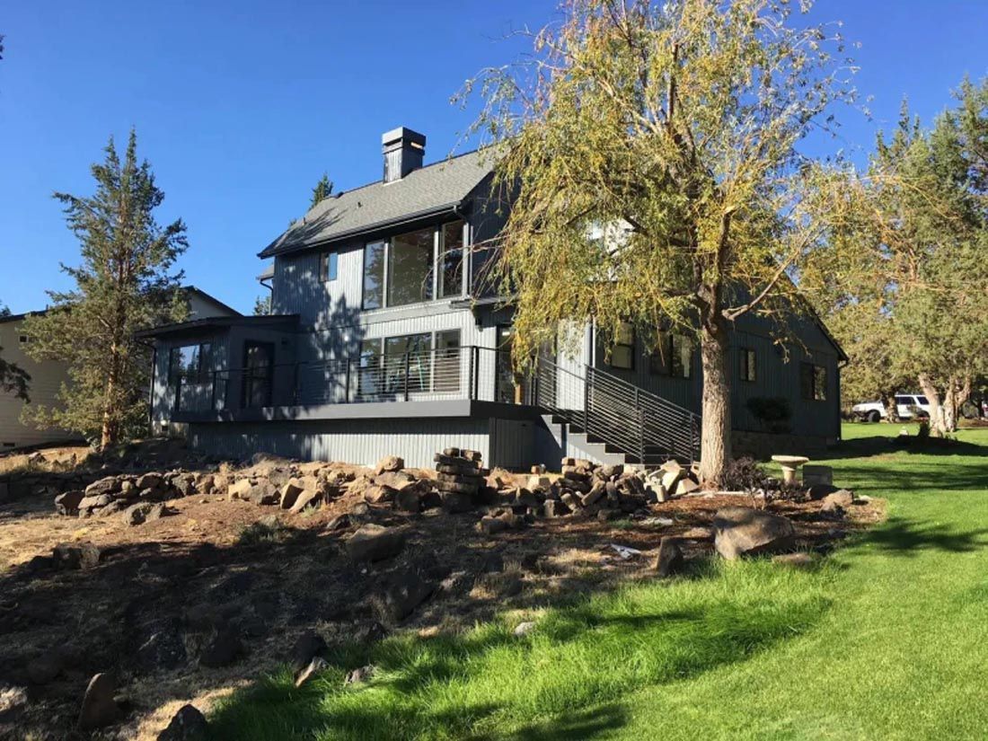 A large house is sitting on top of a lush green field surrounded by trees.