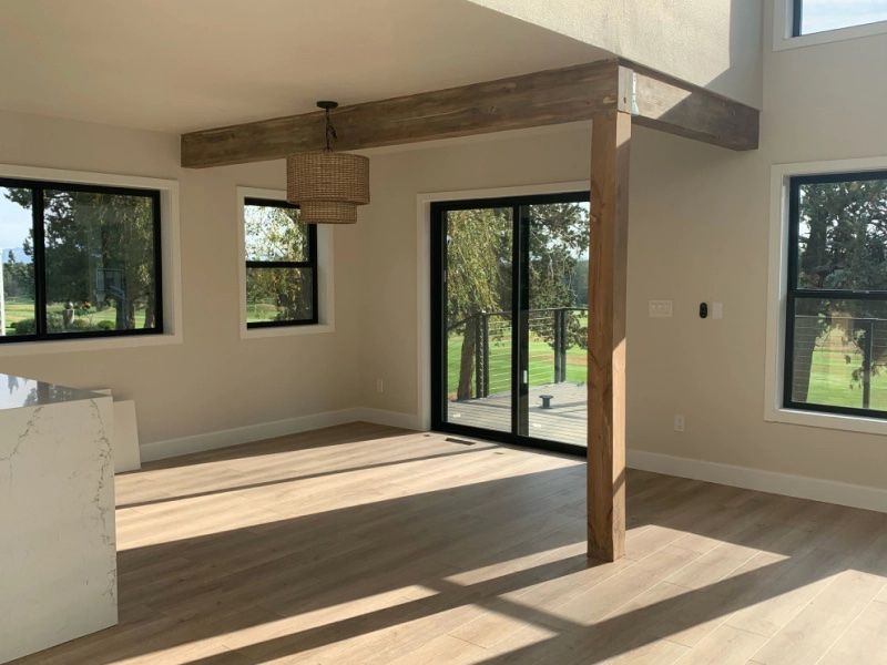 An empty room with a lot of windows and a wooden beam.