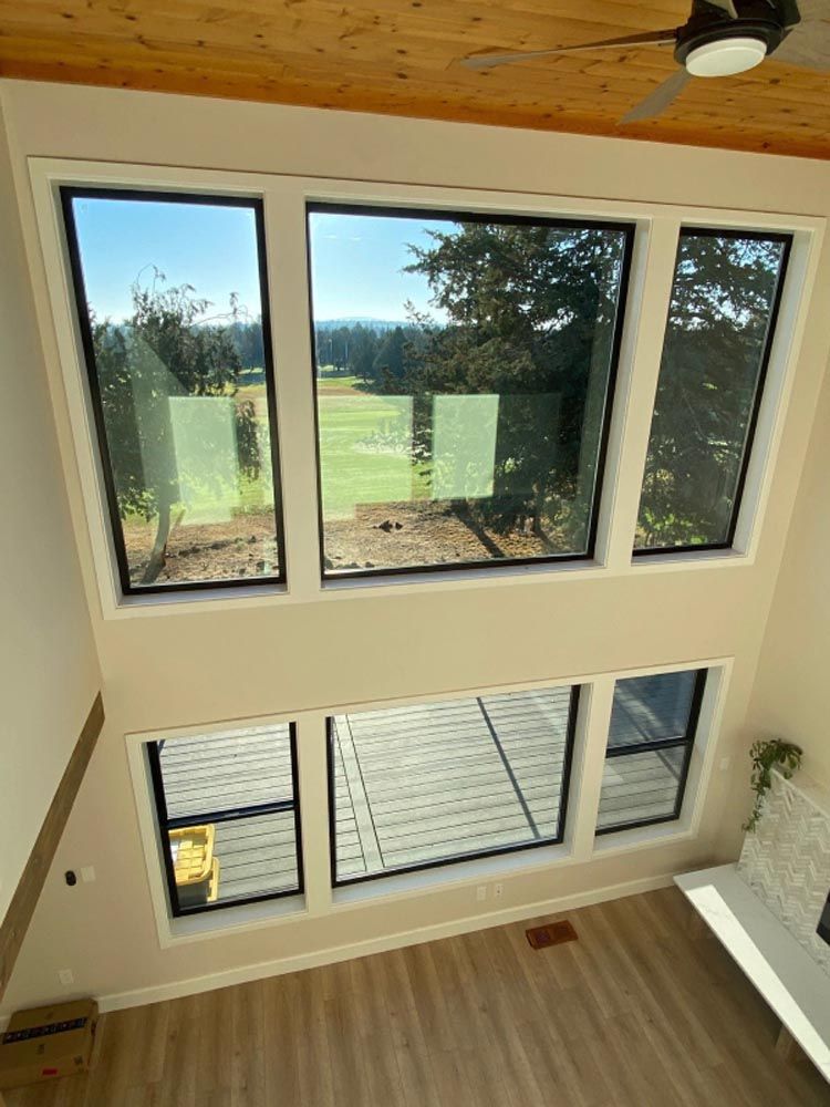 A living room with a lot of windows and a ceiling fan.