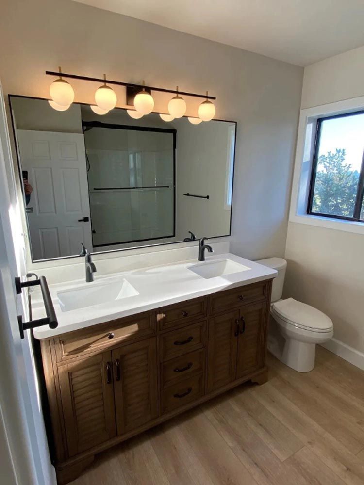 A bathroom with two sinks , a toilet , and a large mirror.