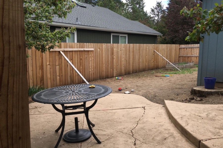 A table and chairs are sitting on a patio in front of a wooden fence.