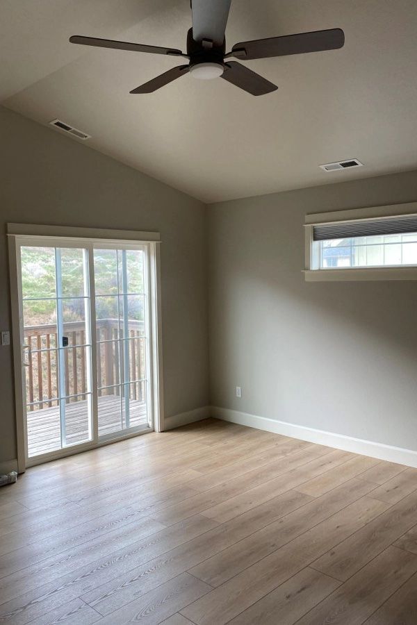 An empty living room with a ceiling fan and sliding glass doors.