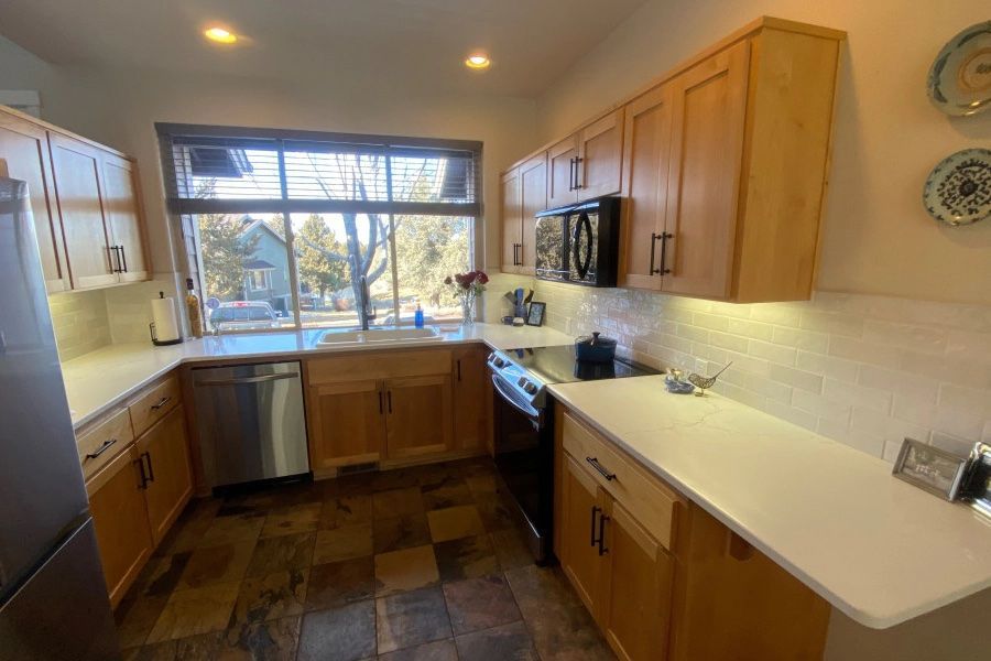 A kitchen with wooden cabinets , stainless steel appliances , and a large window.