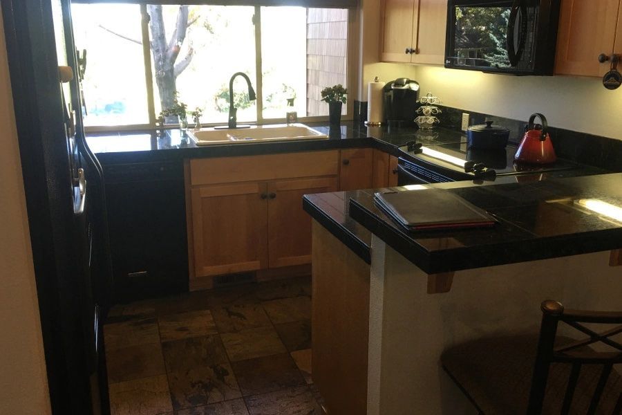 A kitchen with wooden cabinets and black counter tops