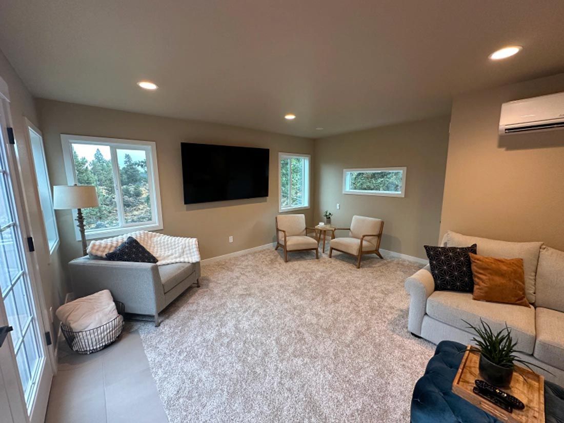 A living room with a couch , chairs , and a flat screen tv.