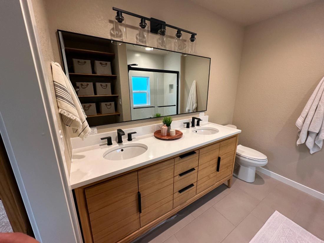 A bathroom with two sinks , a toilet , and a large mirror.
