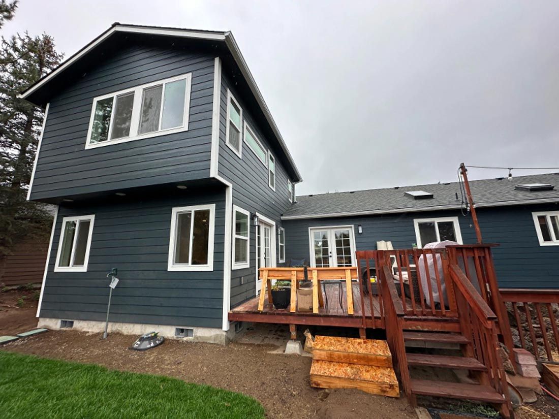 A blue house with a deck and stairs in front of it.