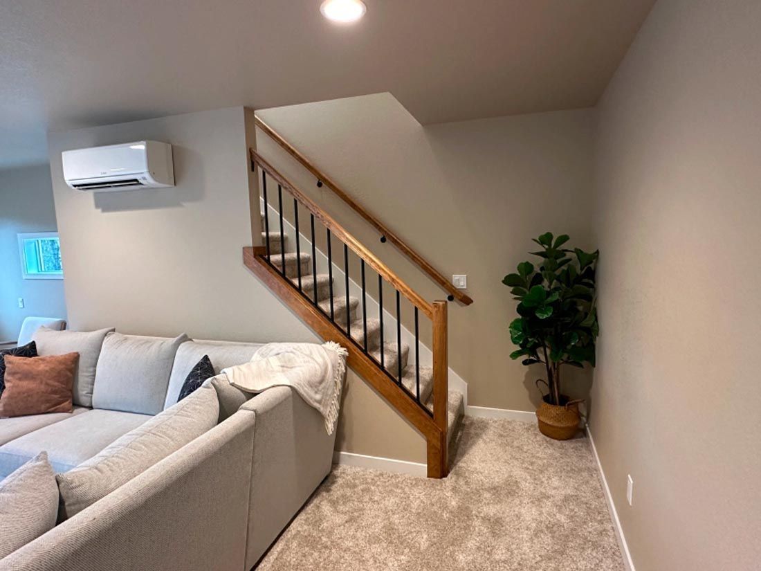 A living room with a couch and stairs leading up to the second floor.