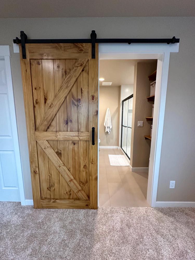 A sliding barn door is open to a bathroom in a basement.
