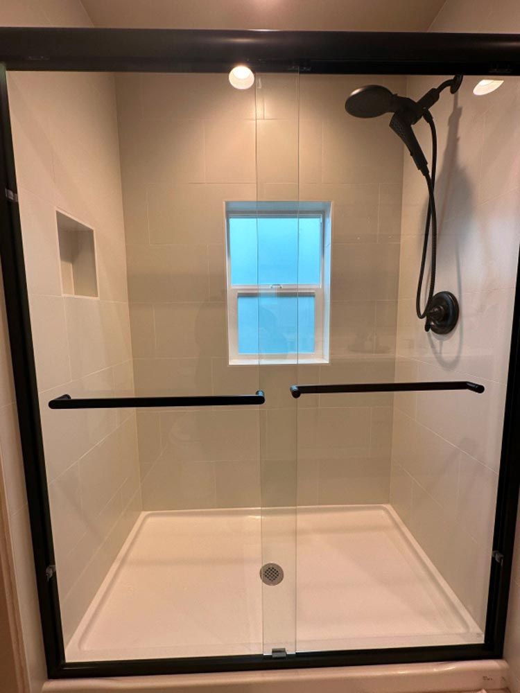 A shower with a sliding glass door and a window.