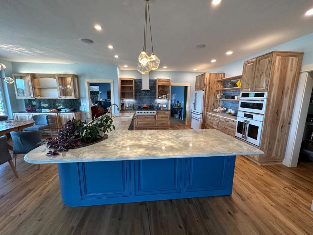 A large kitchen with a blue island in the middle and wooden cabinets.