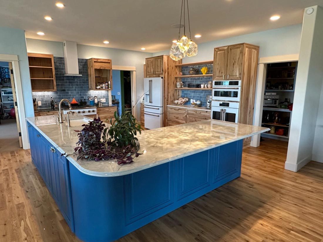 A kitchen with blue cabinets and a large island in the middle.