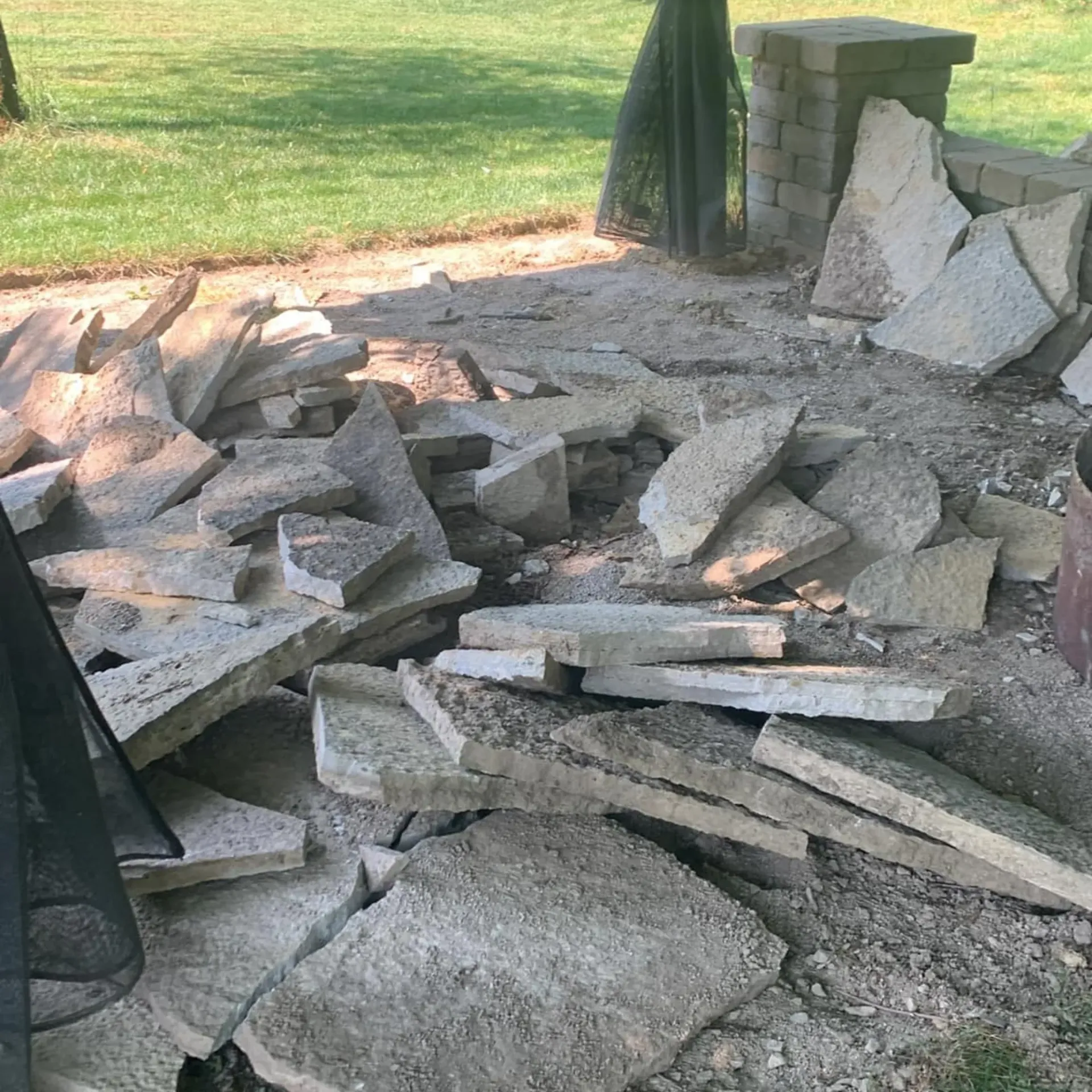 Hall's Hauling -A pile of rocks is sitting on the ground in a yard.