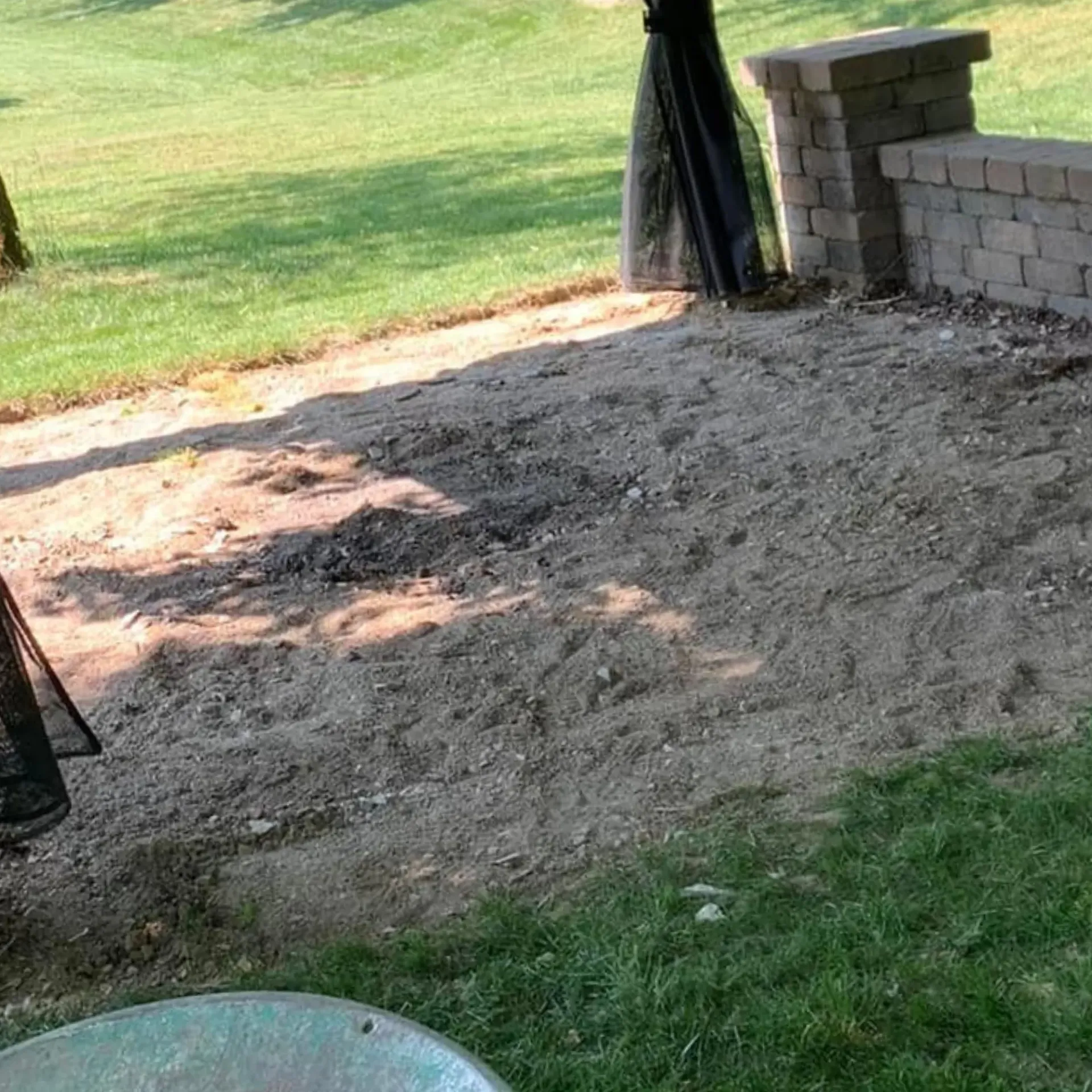 Hall's Hauling -A brick wall is sitting next to a sandy area in a park.