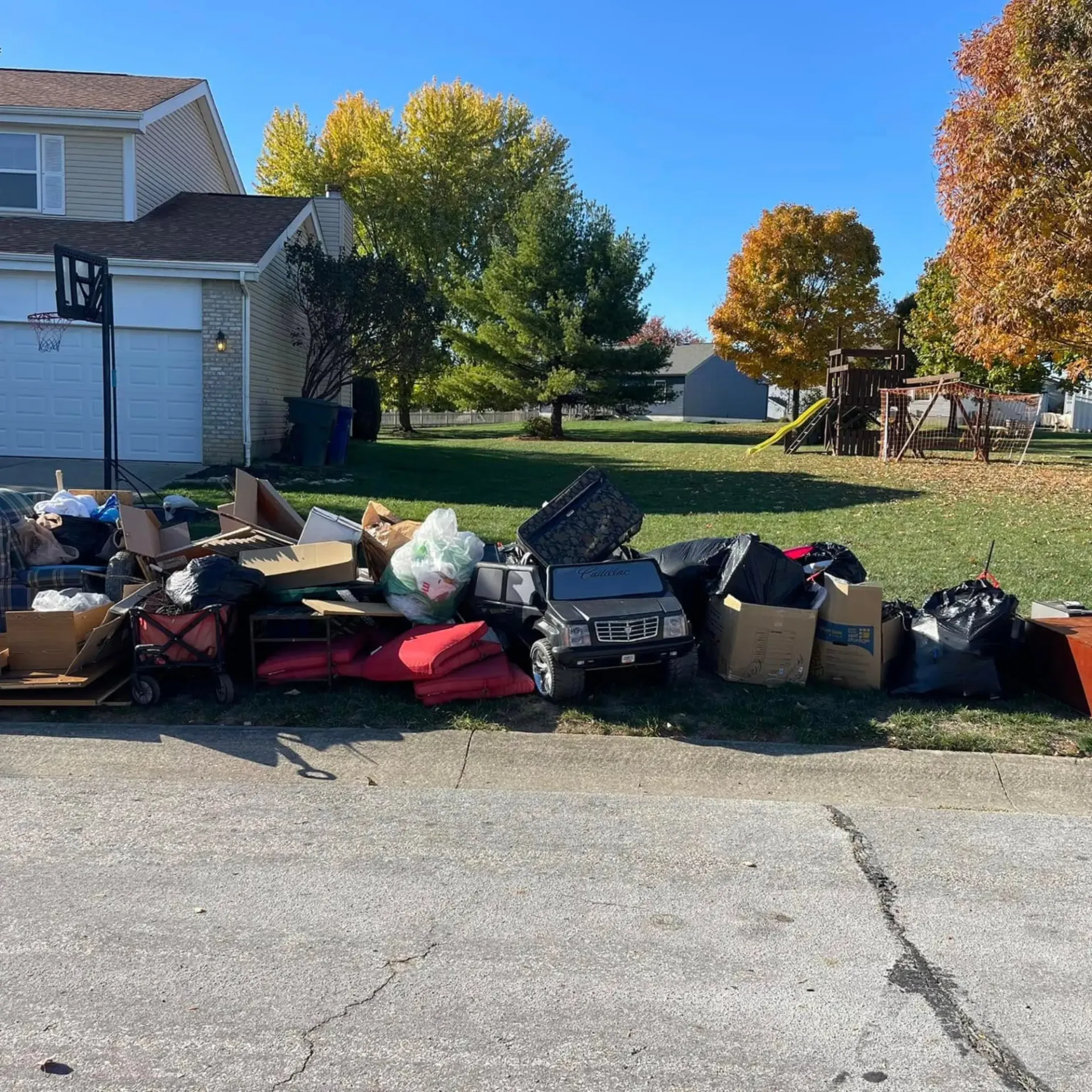 Hall's Hauling -A pile of trash is sitting on the side of the road in front of a house.