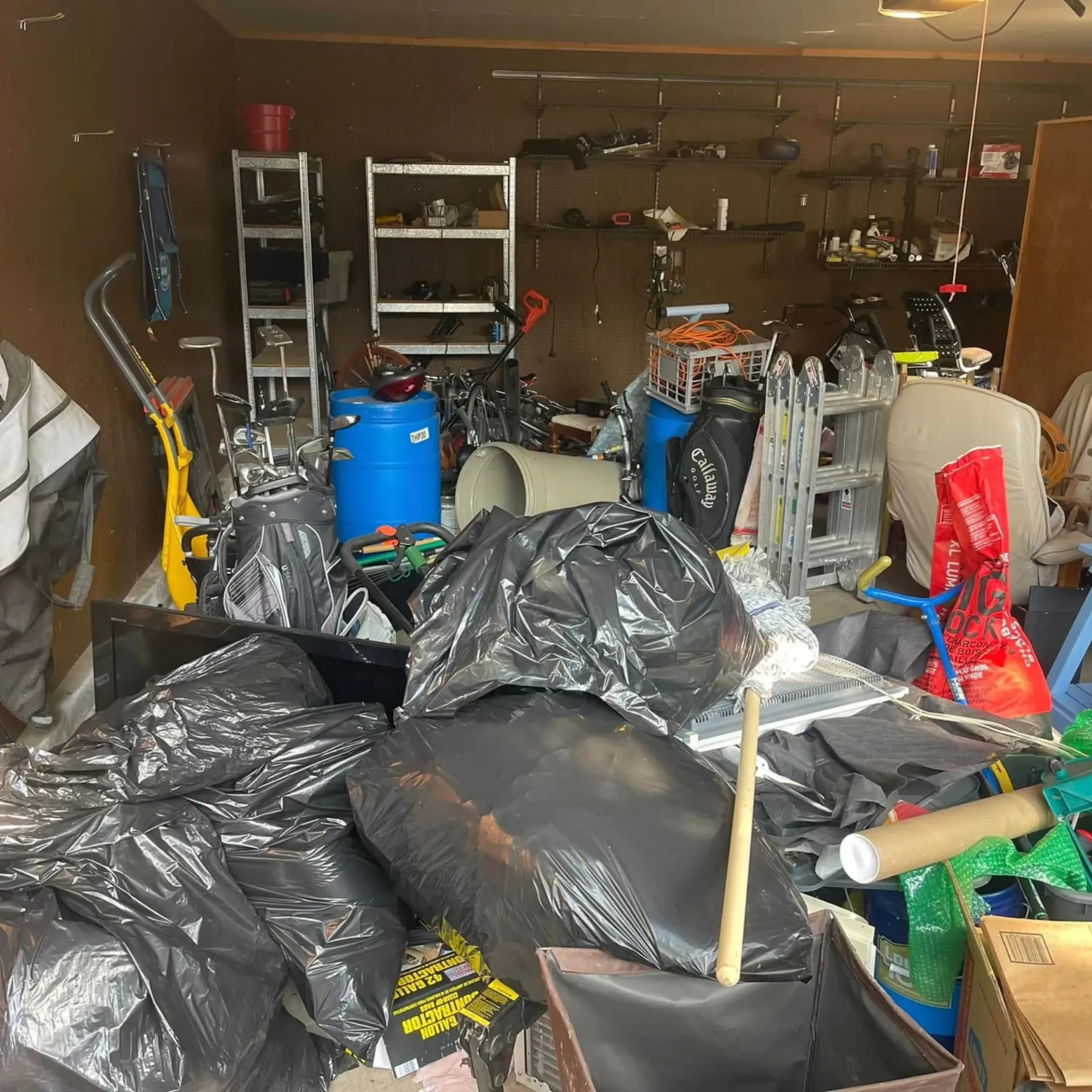 Hall's Hauling -A garage filled with lots of trash bags and boxes.