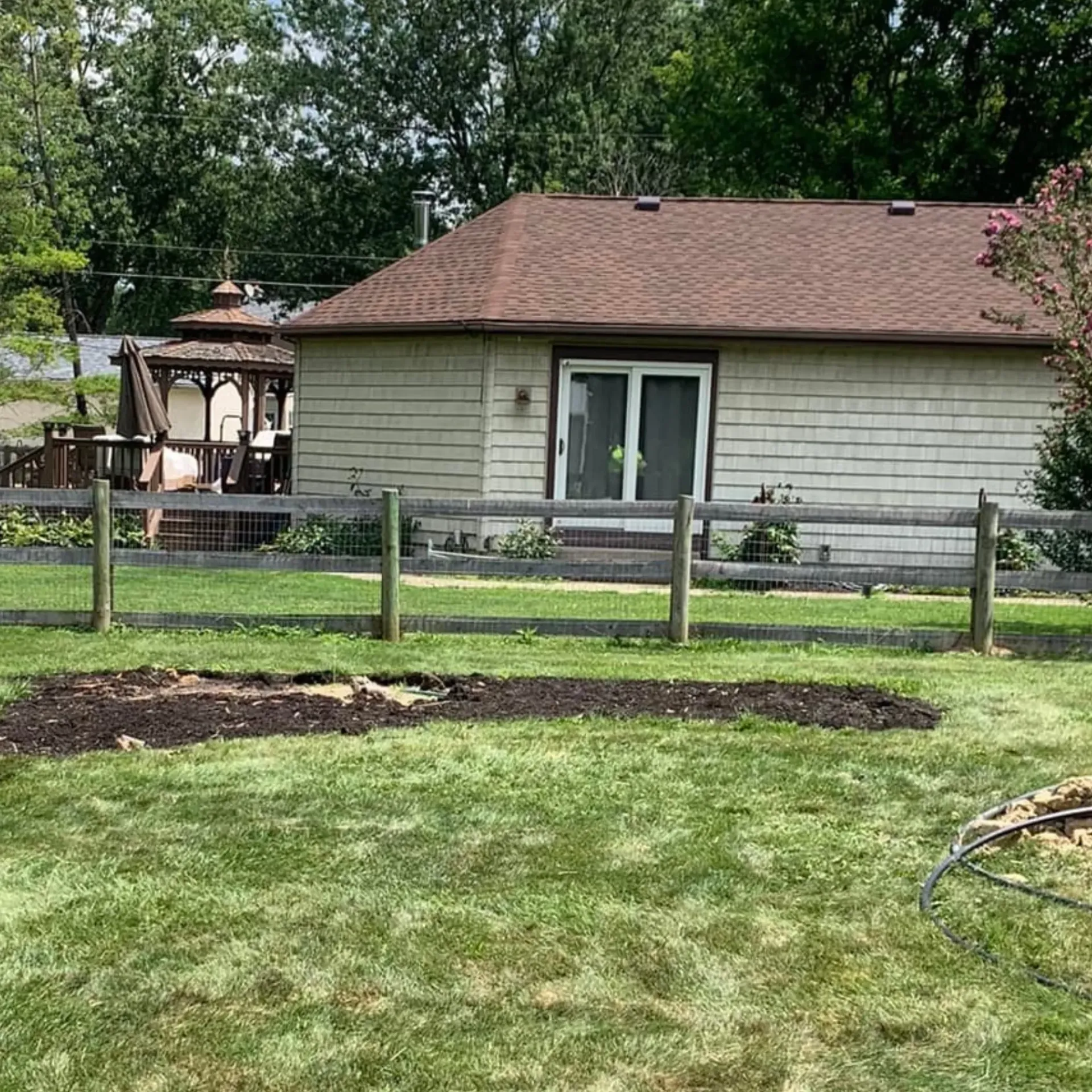 Hall's Hauling -A wooden fence surrounds a lush green yard in front of a house.