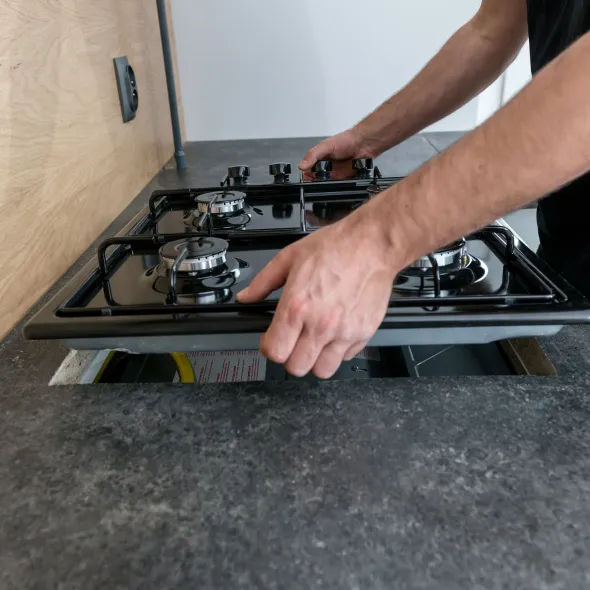 Hall's Hauling -A man is working on a gas stove in a kitchen