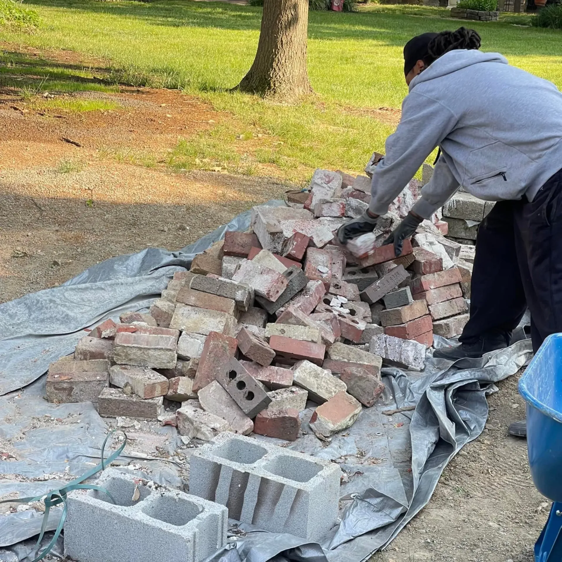 Hall’s Hauling - A man is standing next to a pile of bricks.