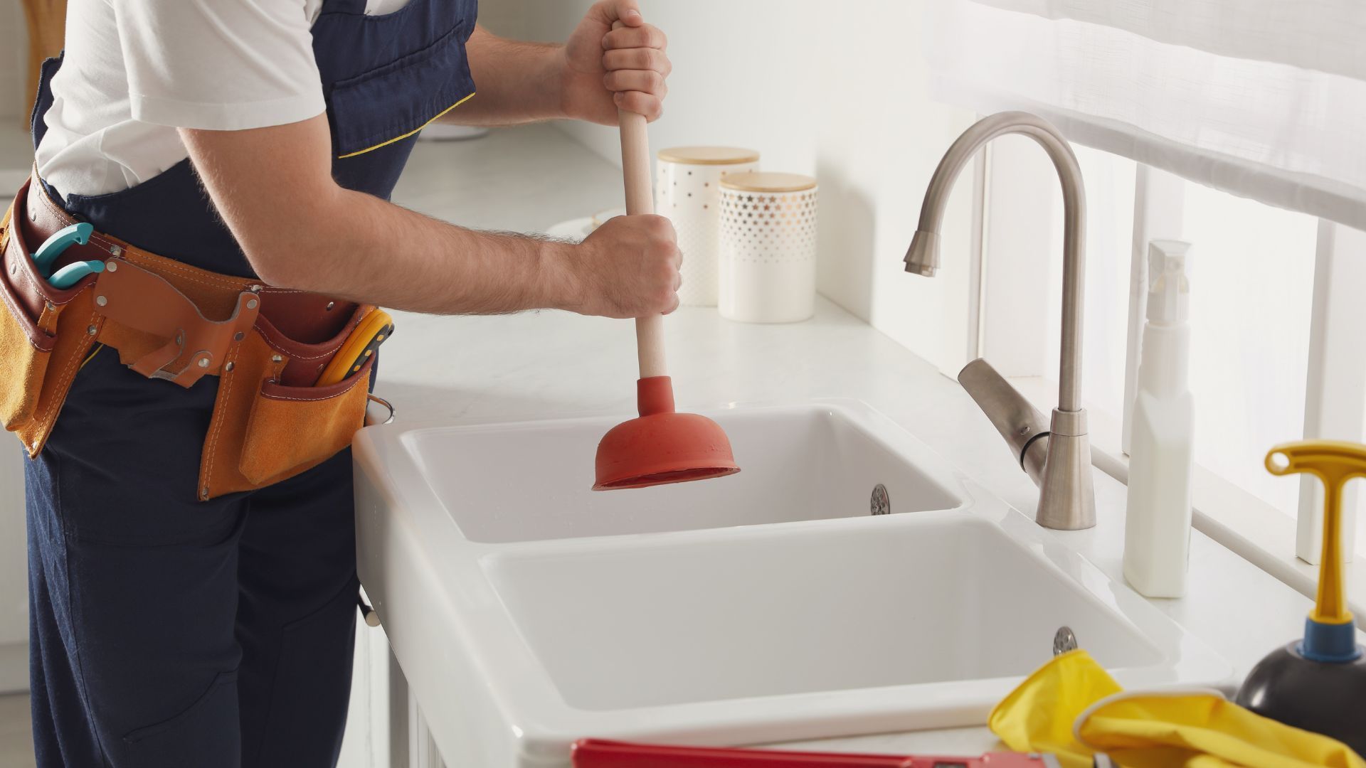 A plumber is using a plunger to fix a kitchen sink.