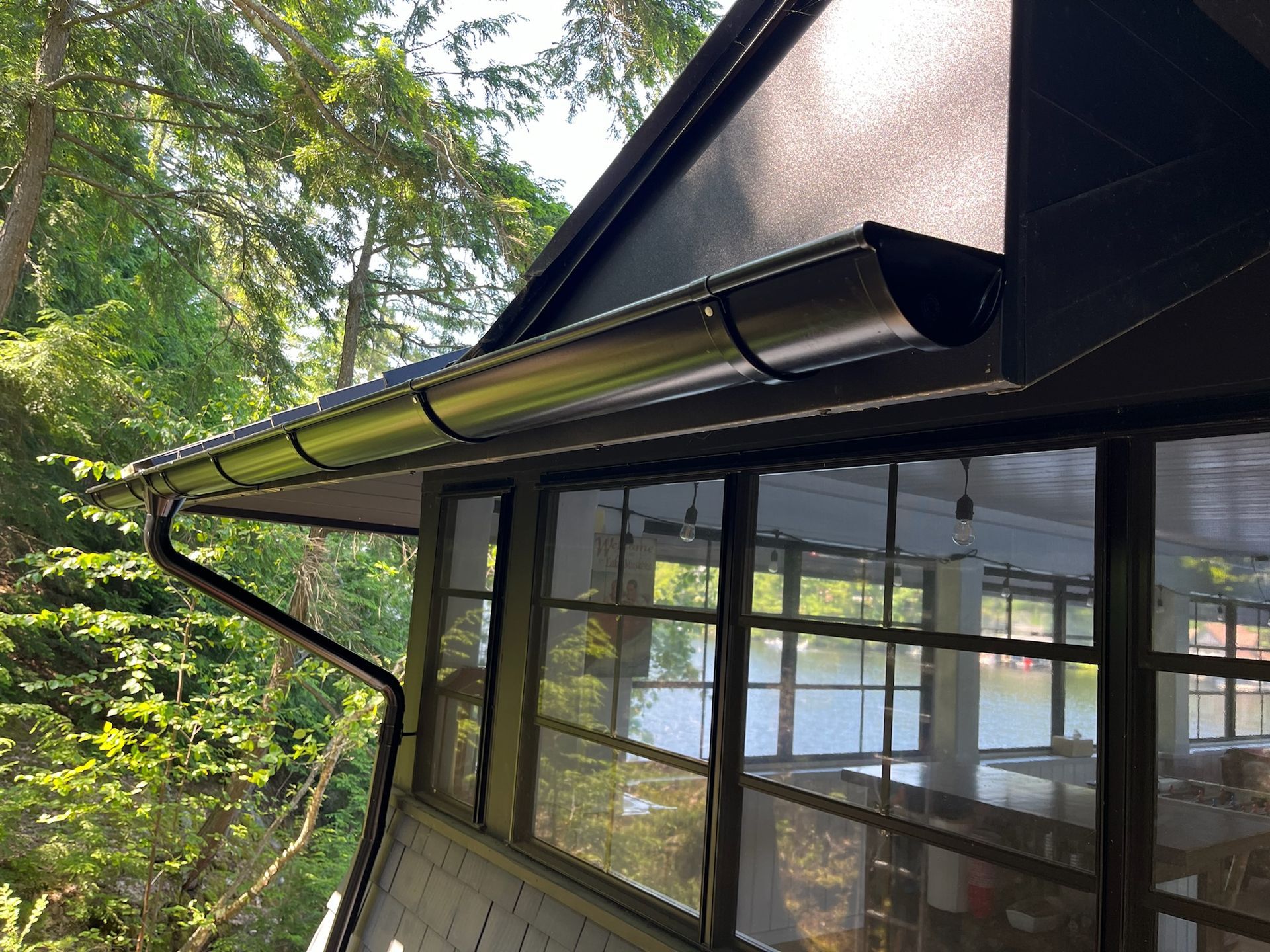 Black gutters on a building with screen windows overlooking a lake.