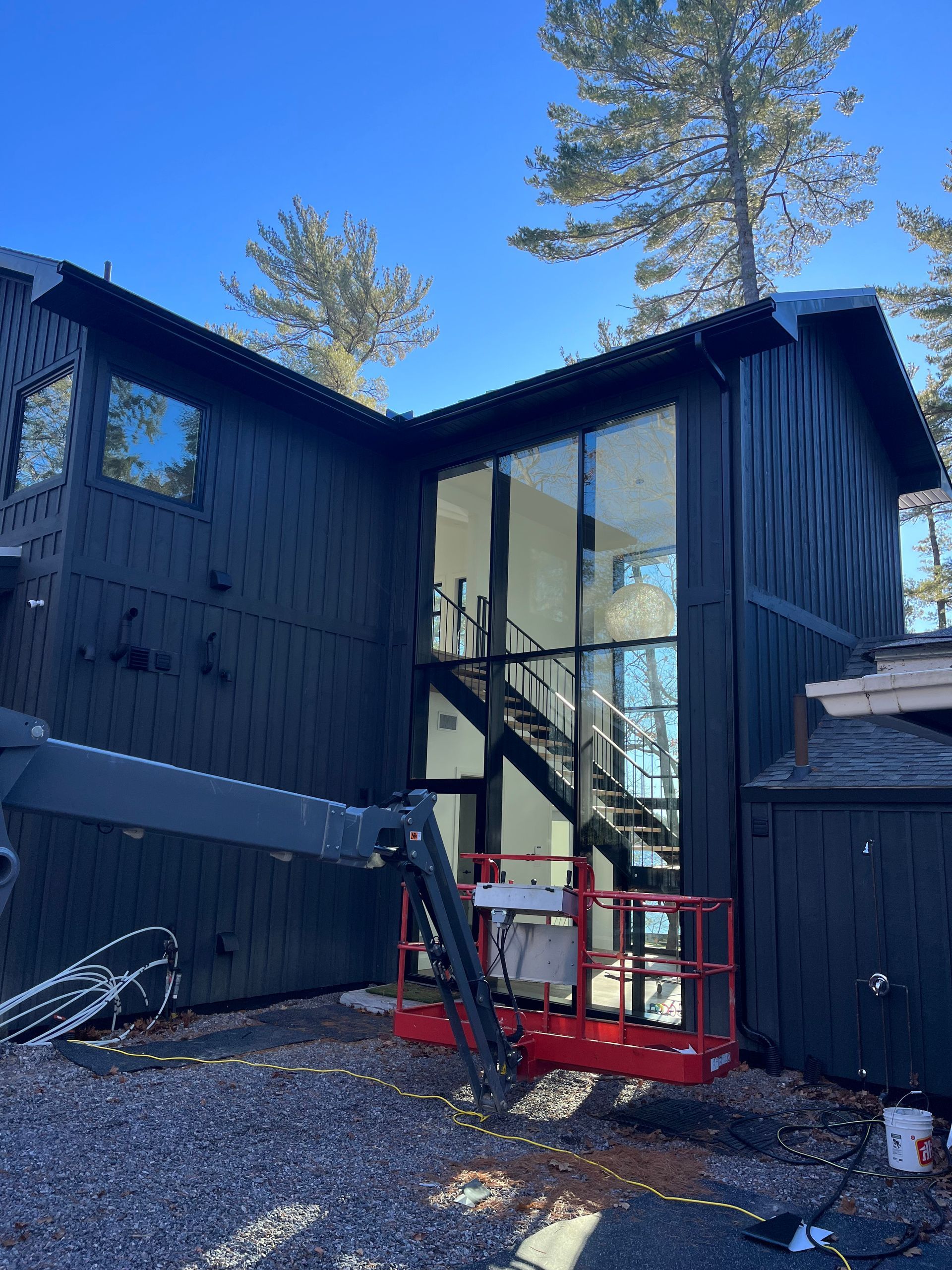A large black house with a red crane in front of it.