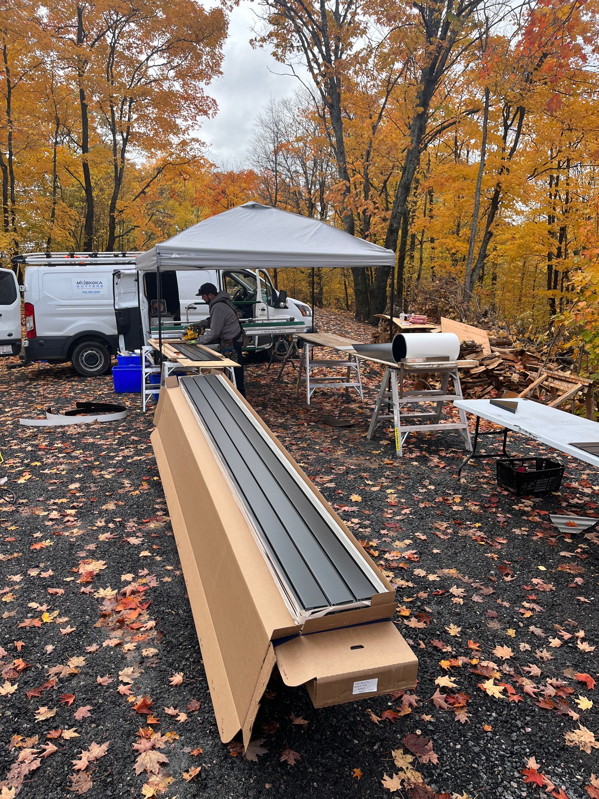 A man is sitting under a canopy in the woods.