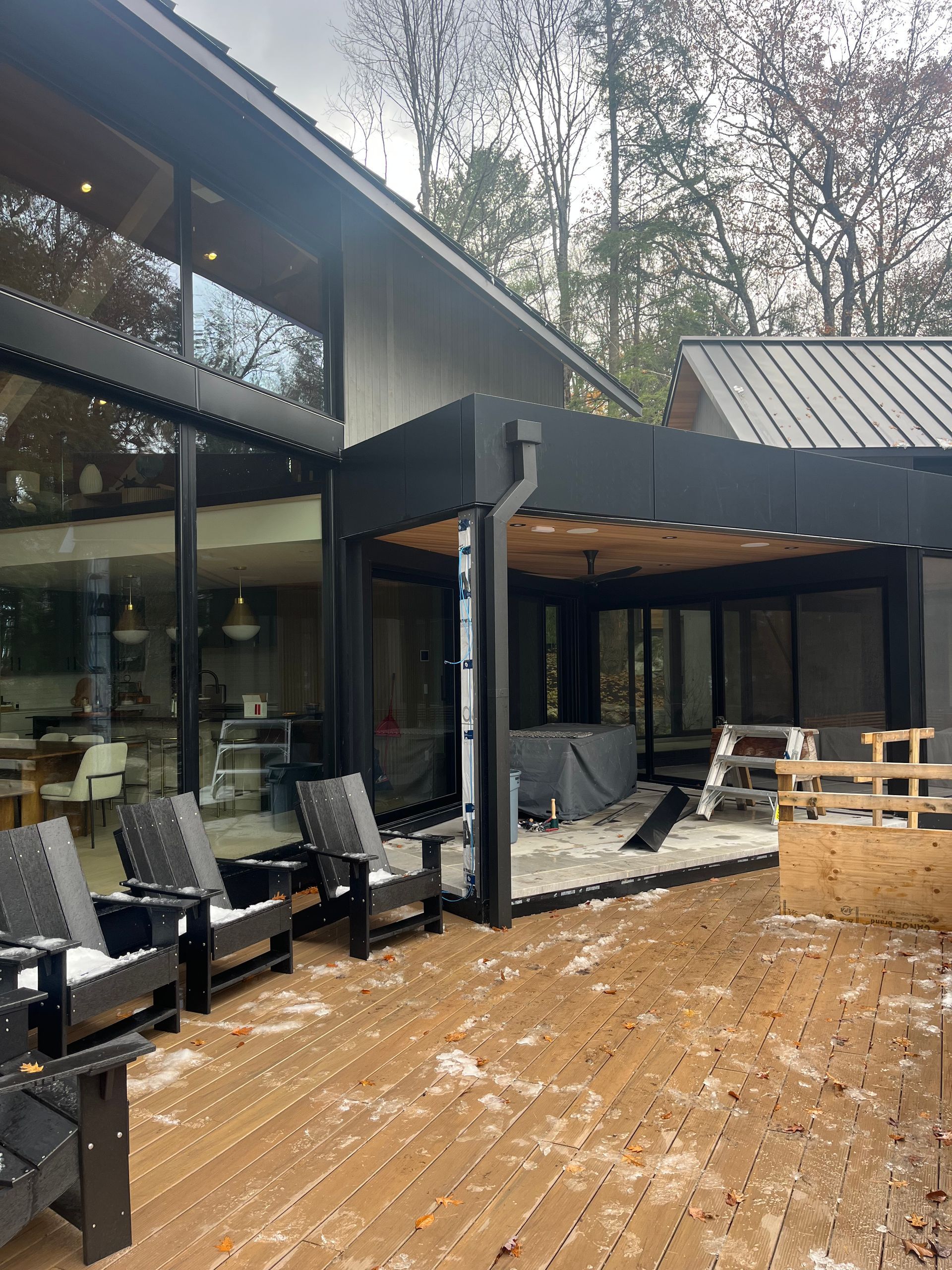 A wooden deck with chairs and a fence in front of a house.