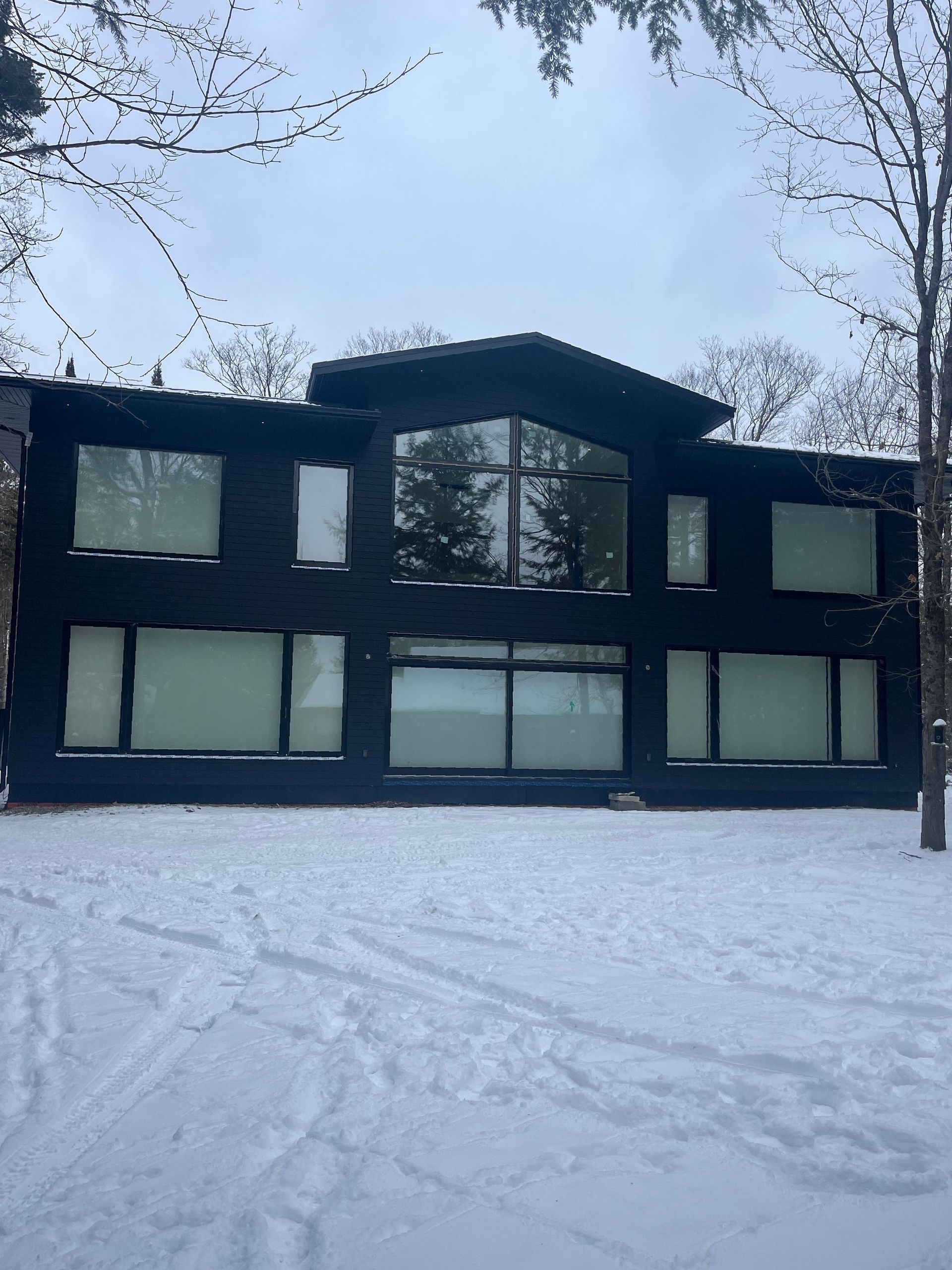 A large black building with a lot of windows is covered in snow.
