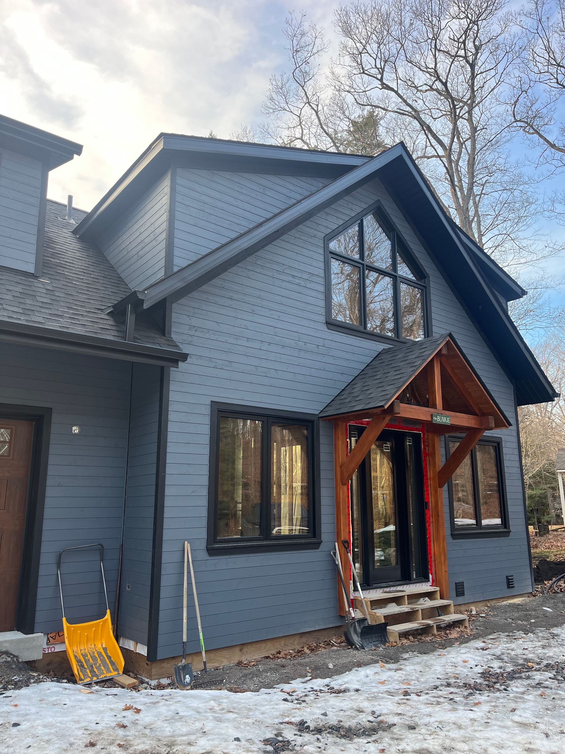 A large house with a lot of windows is sitting in the snow.