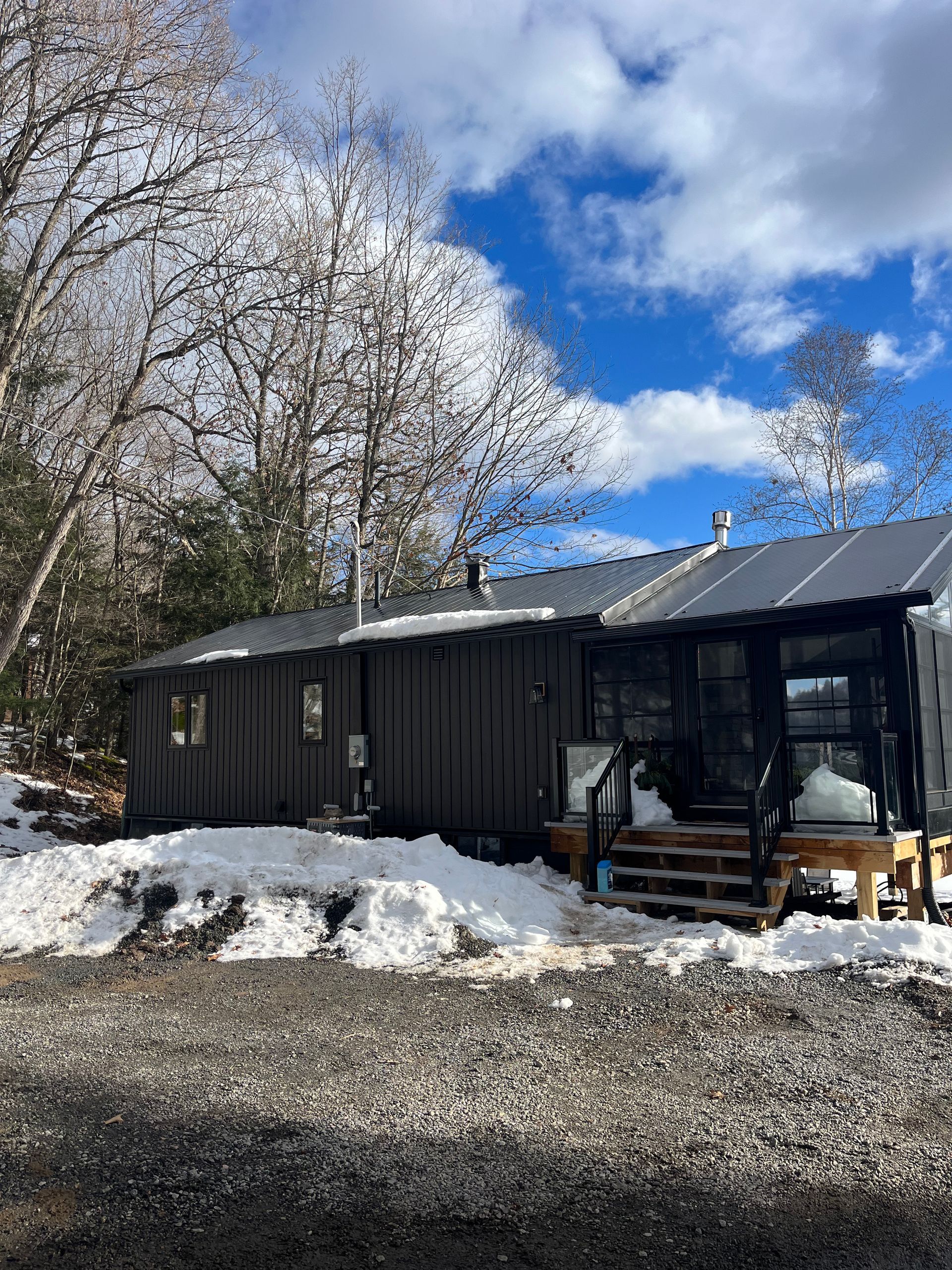 A small house is sitting in the middle of a snow covered field.