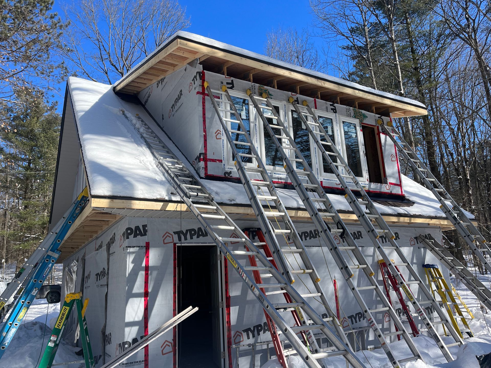 A house is being built in the snow with a lot of ladders.