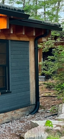 A house with a black gutter on the side of it.