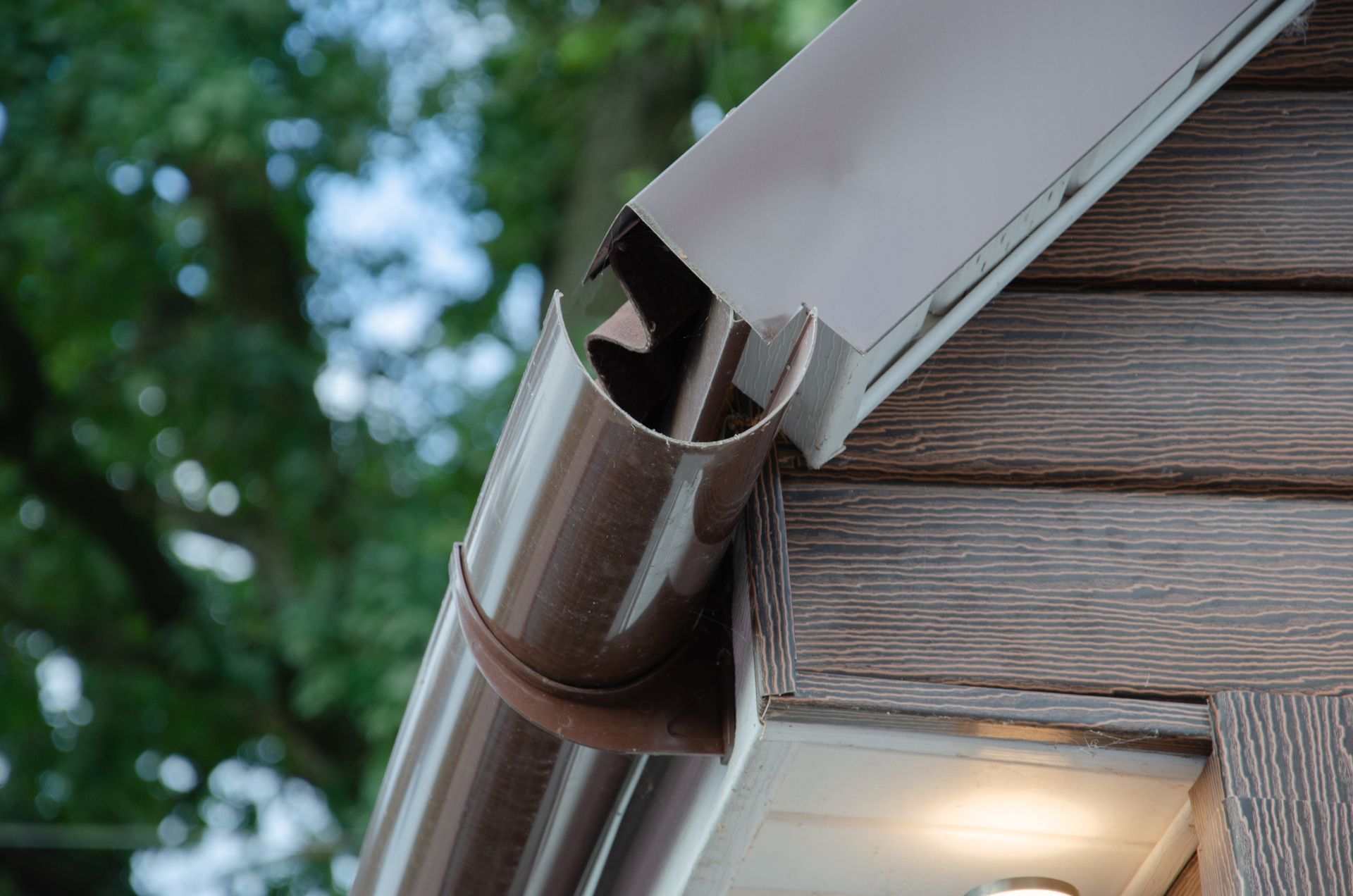 A brown gutter is attached to the side of a house.