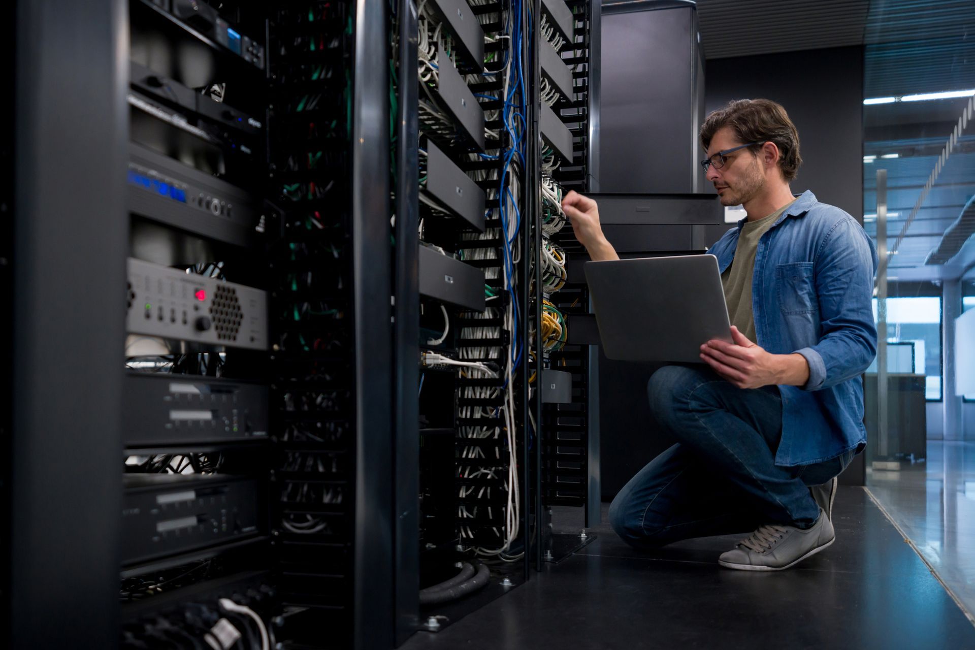 An IT support technician fixing a network server at an office.