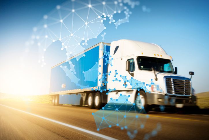 A semi truck is driving down a highway with a map of the world behind it.