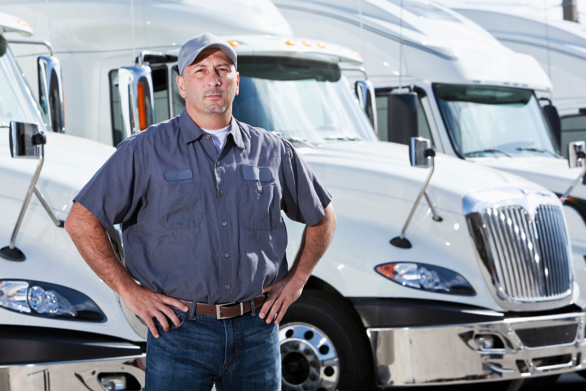 A man is standing in front of a row of semi trucks.