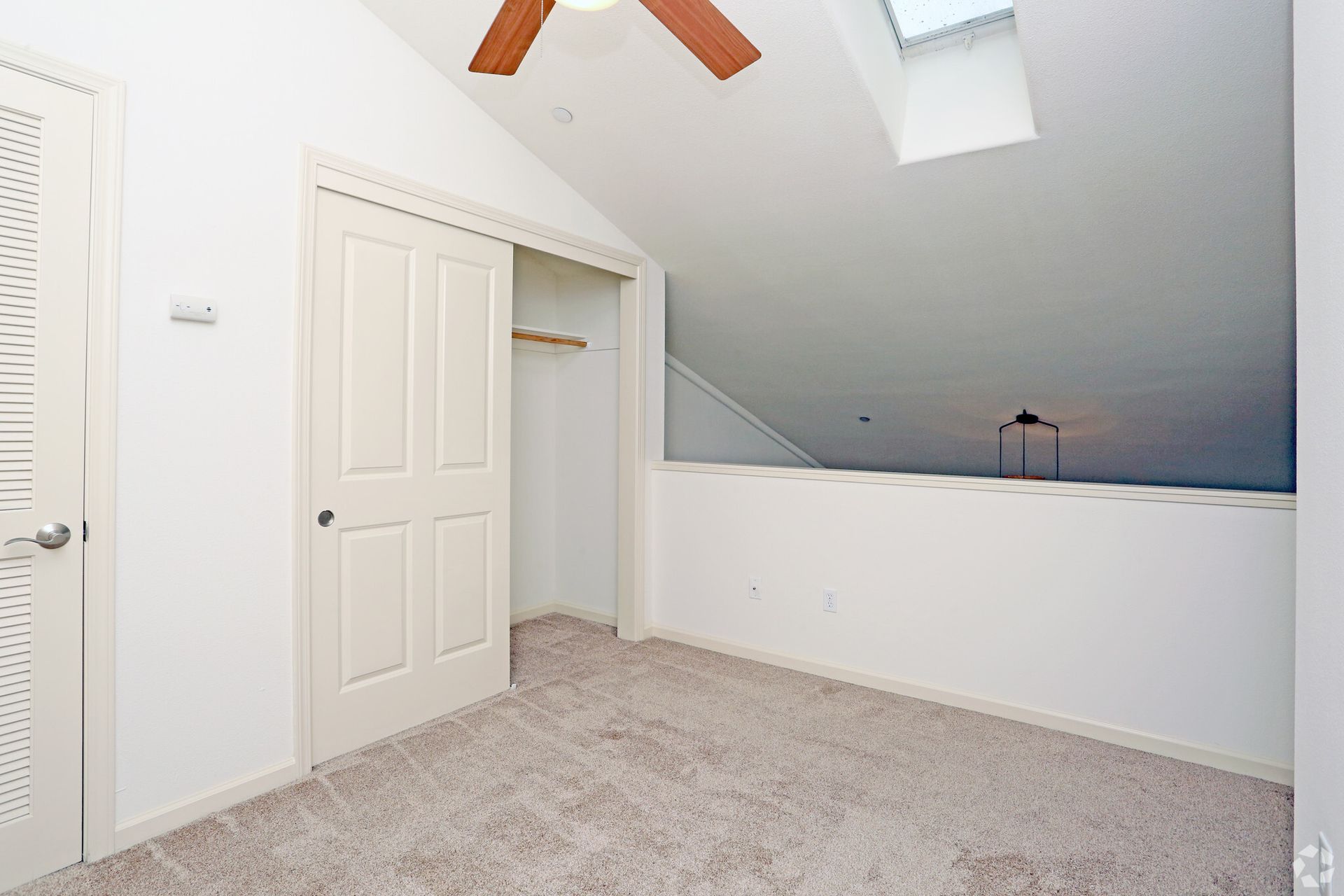 An empty bedroom with a ceiling fan and a skylight