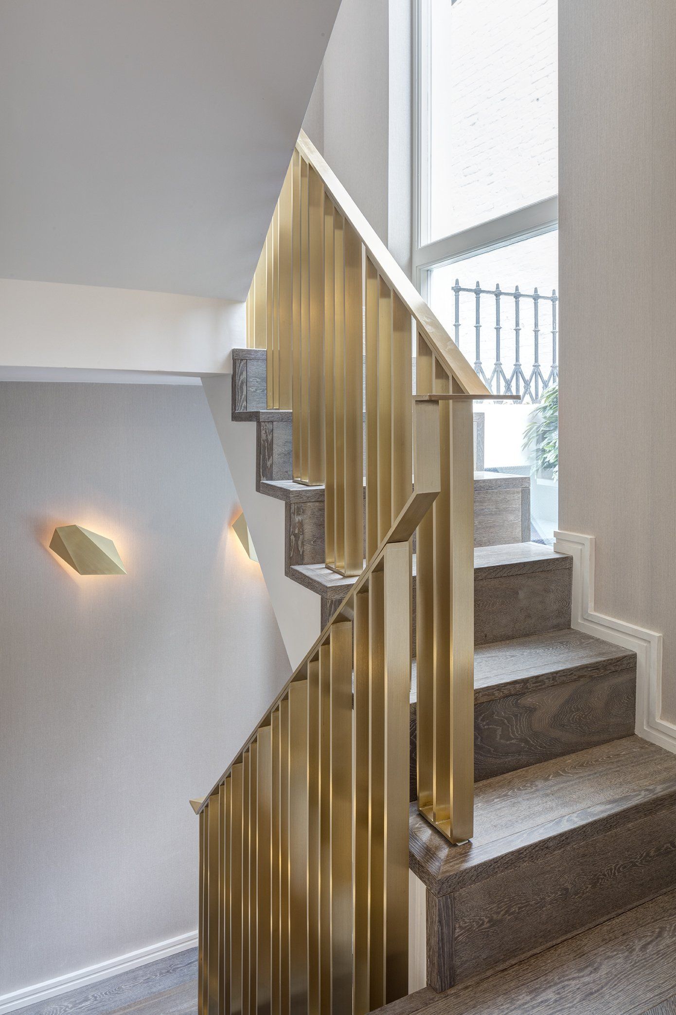 A staircase with a brass railing and a window