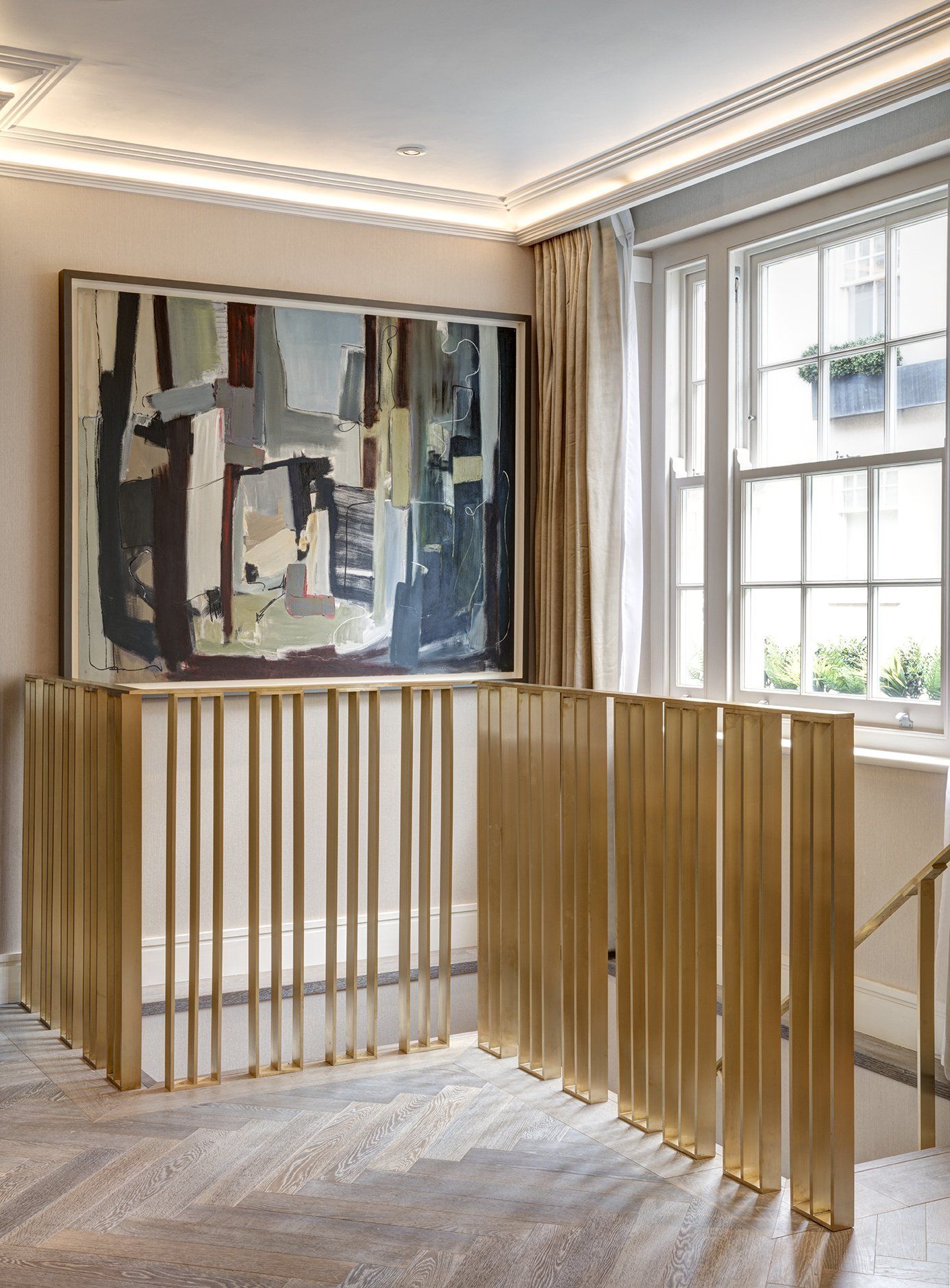 A room with a painting on the wall and a gold railing