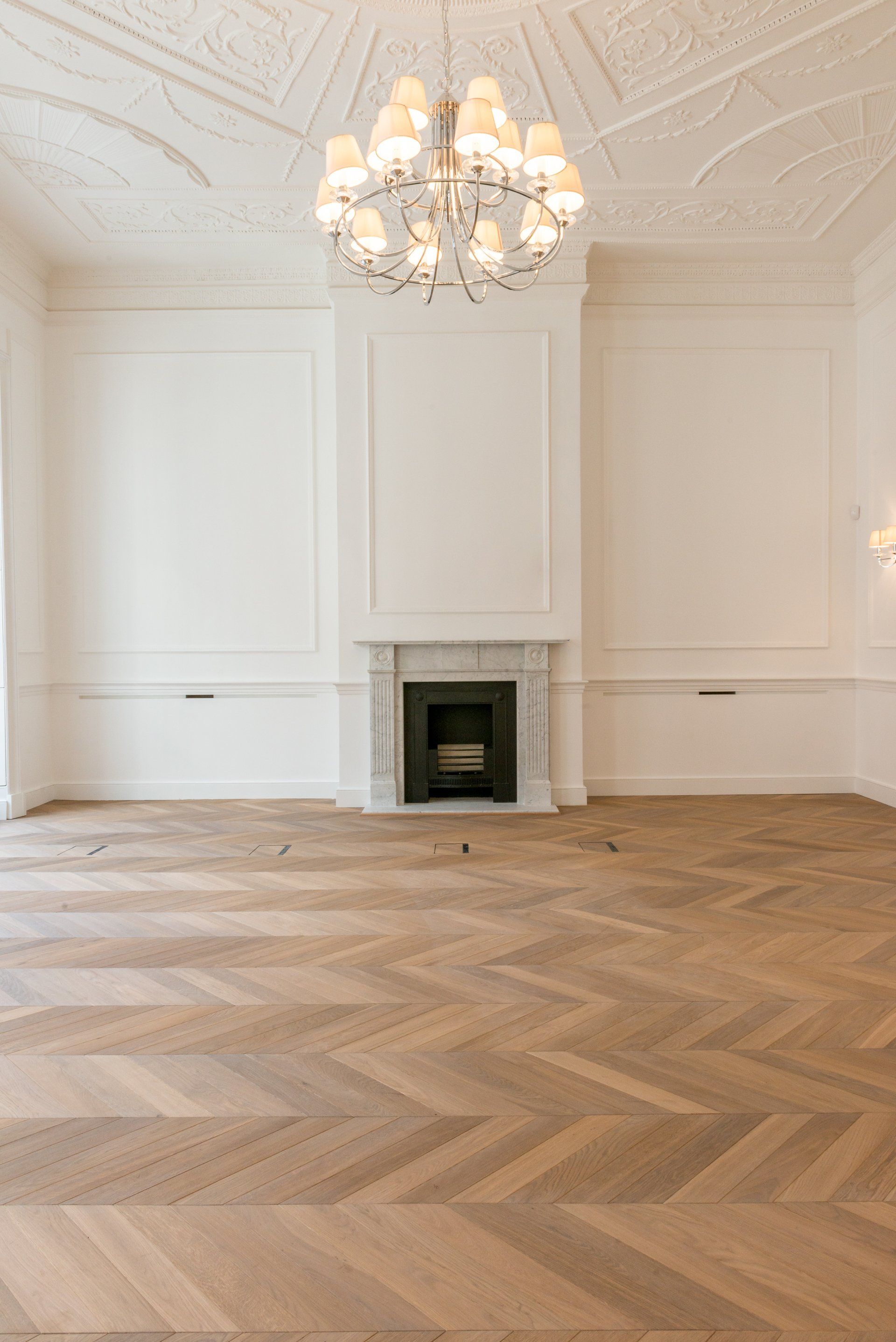 An empty room with a fireplace and a chandelier