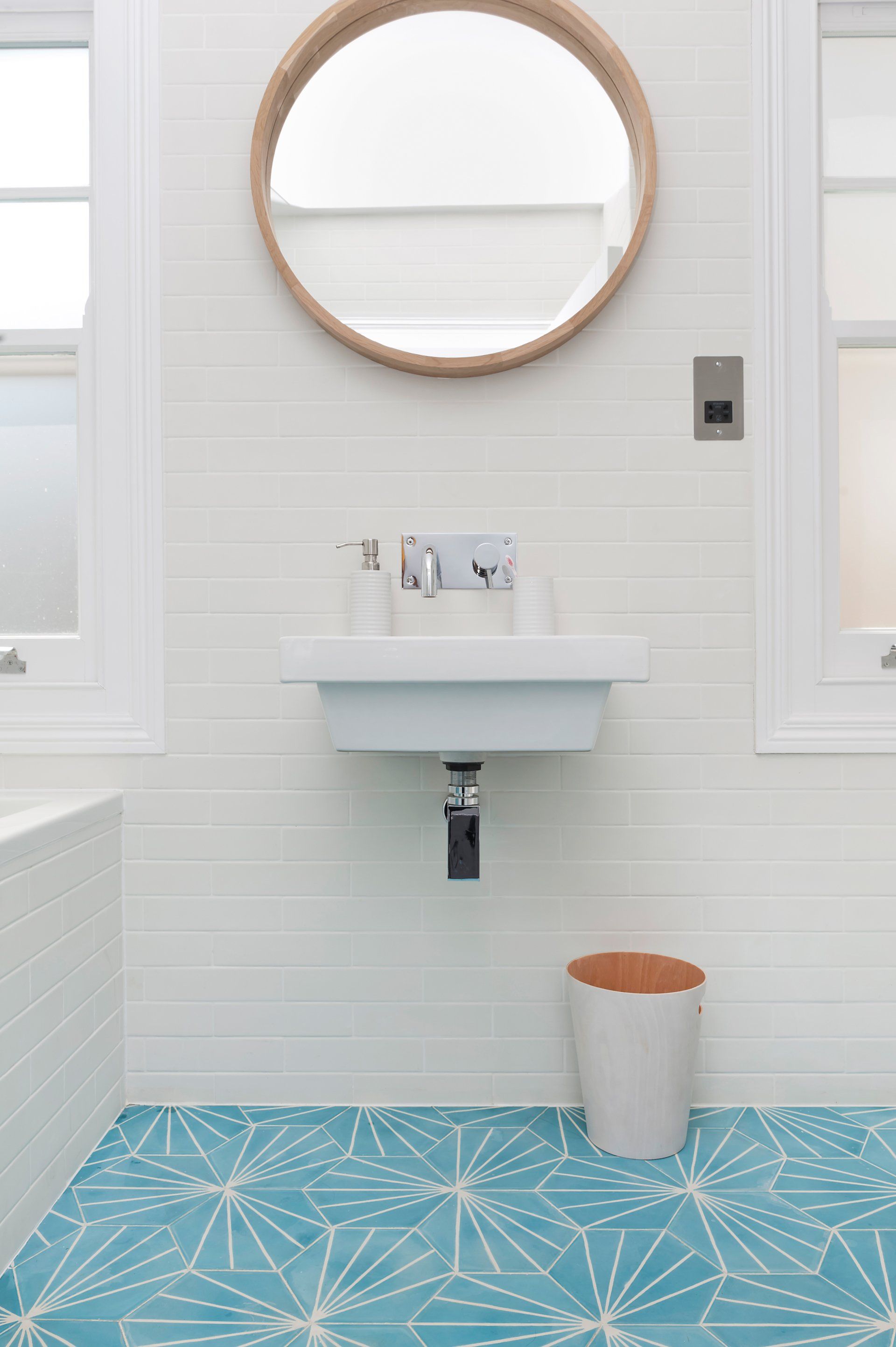 A bathroom with a sink and a round mirror