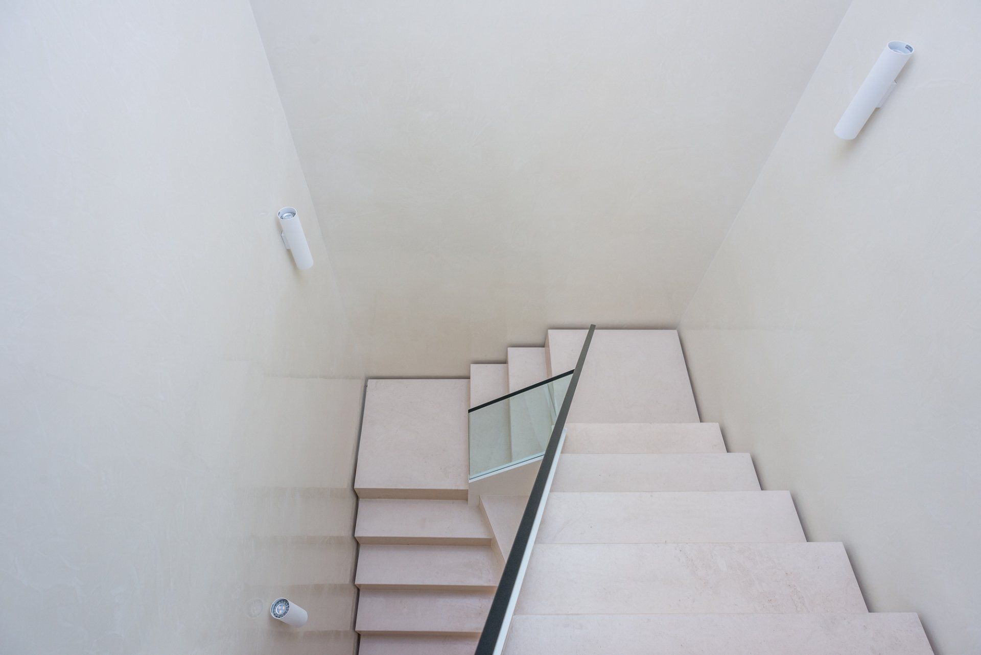 A staircase with a glass railing and a white wall