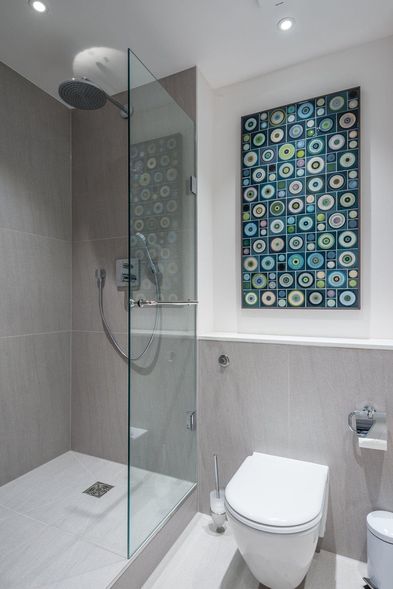 A bathroom with a toilet a shower and a painting on the wall