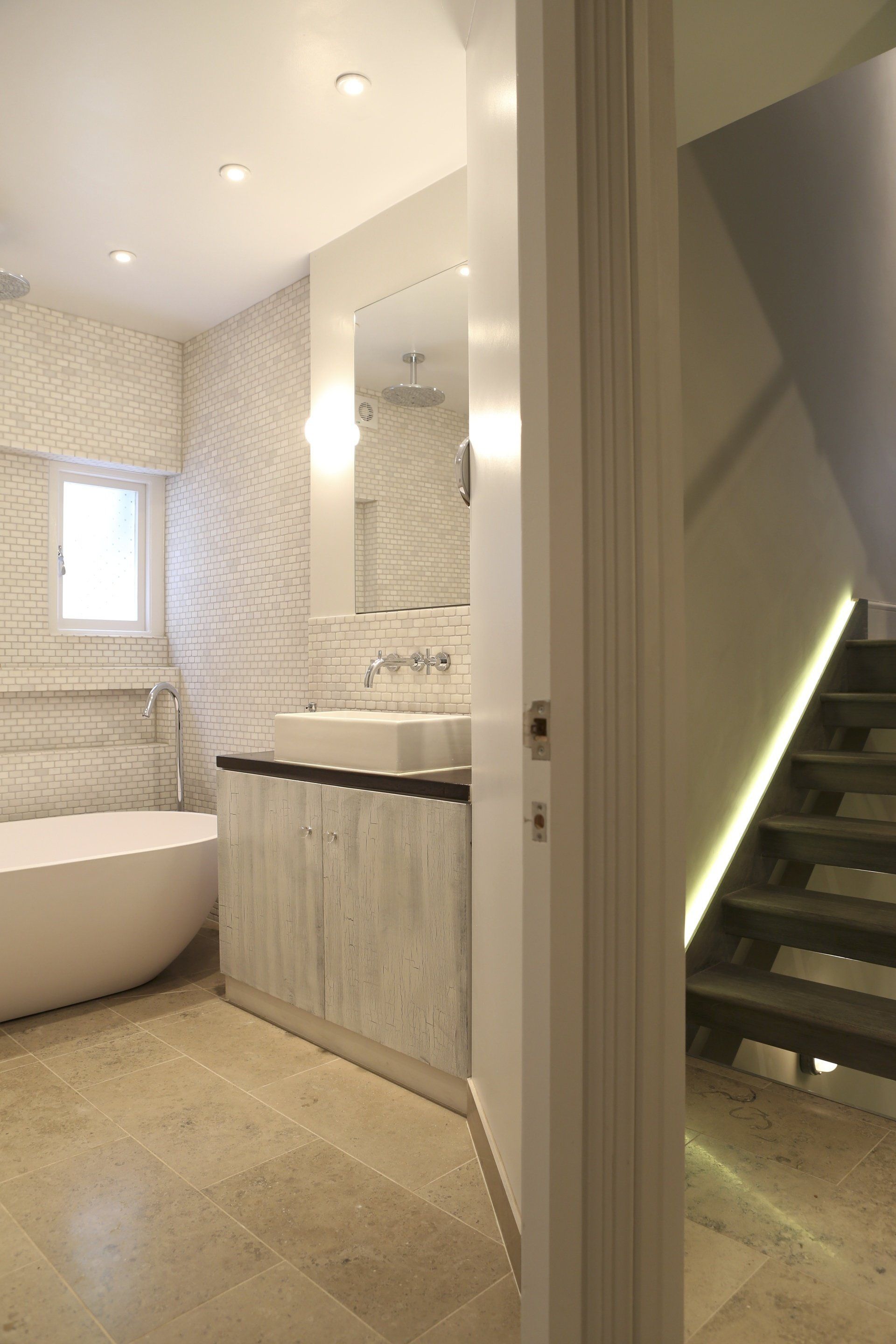 A bathroom with a sink and stairs in the background
